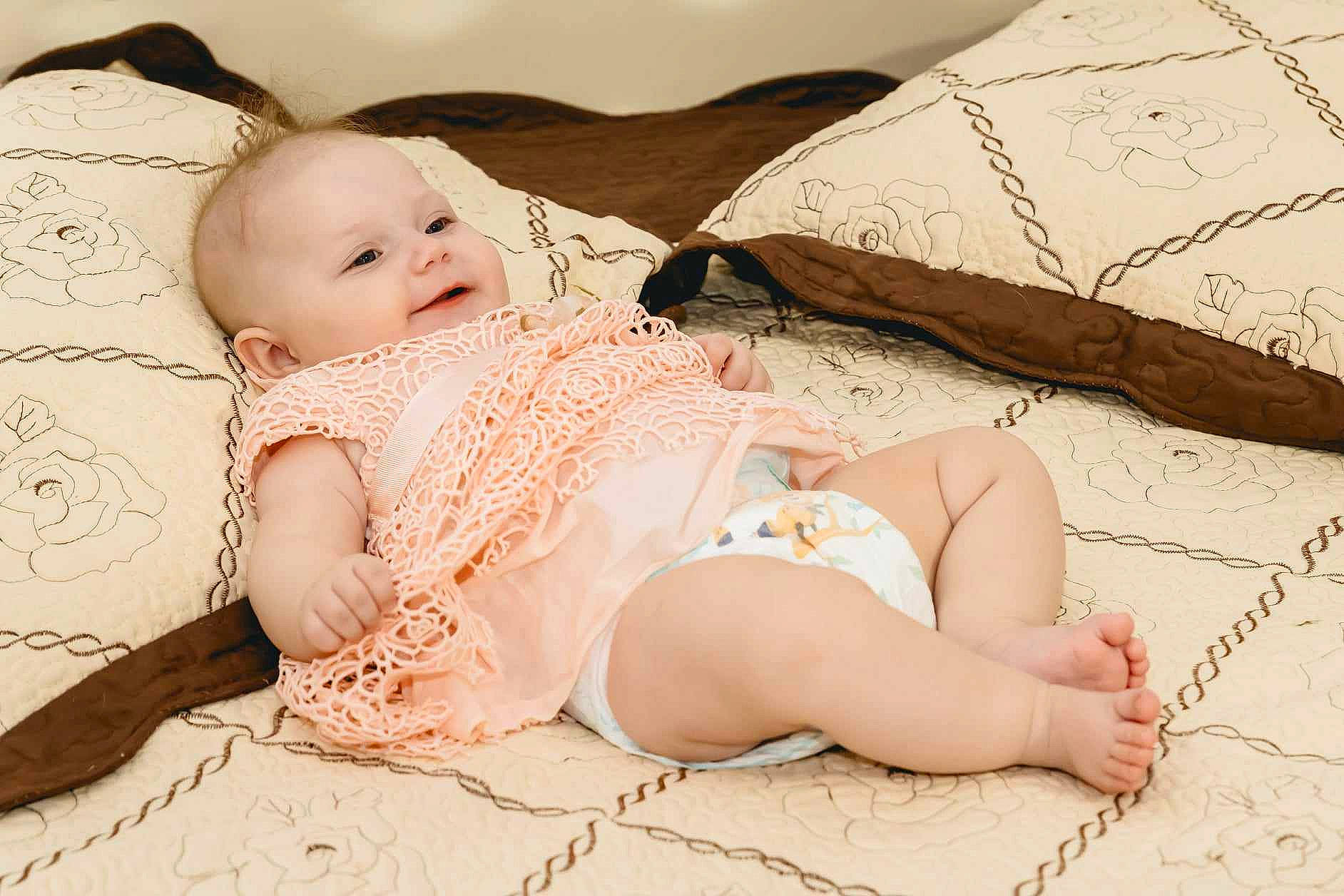 Amélie participe au concours pour gagner de l'argent avec cette photo : baby, baby_sleeping, baby_toddler_clothing, child, comfort, embellishment, fashion_accessory, finger, foot, happy, headband, headpiece, human_leg, linens, pattern, person, pink, sitting, skin, thigh