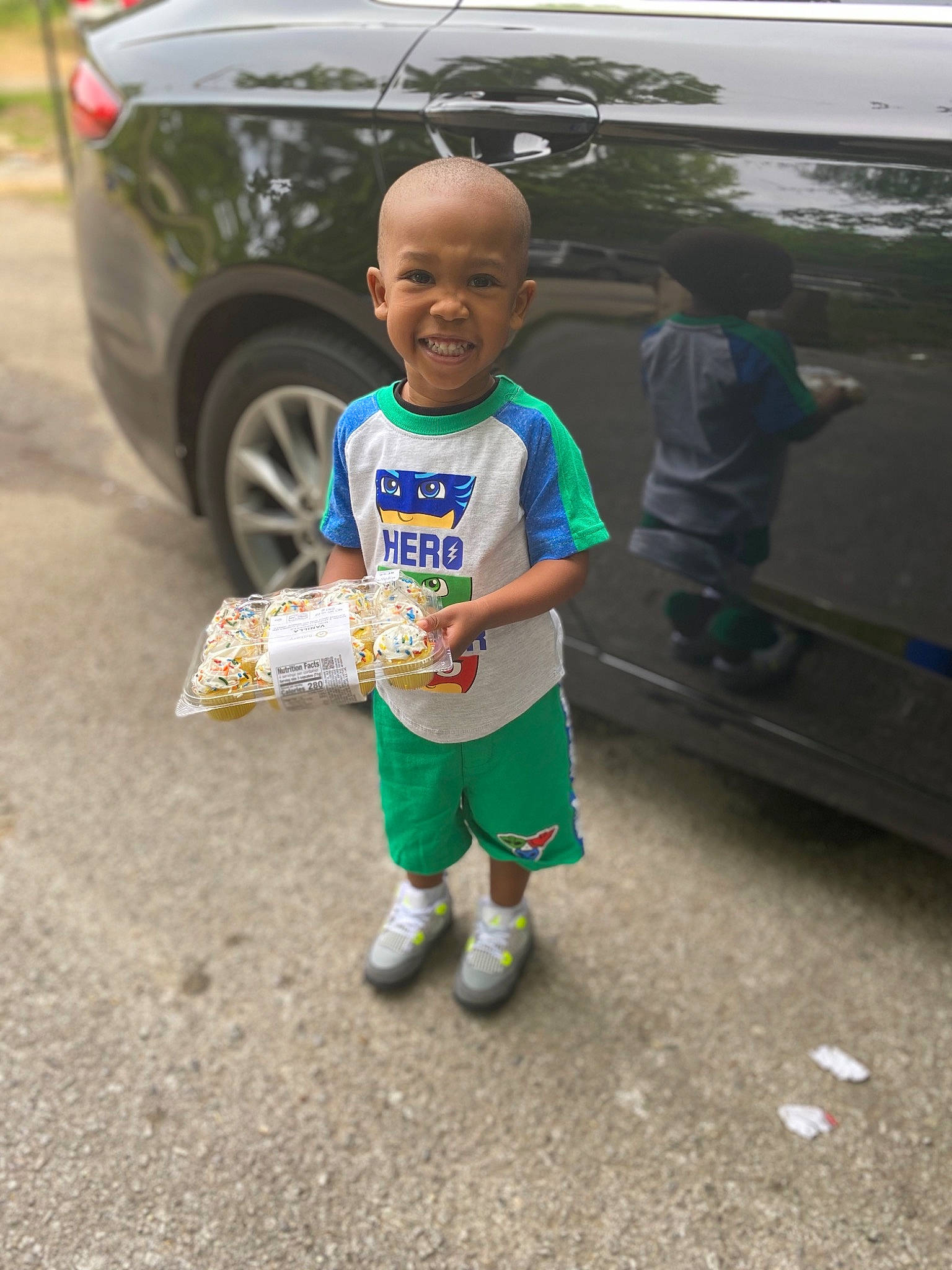 Carter is registered to the contest to win money with this photo: asphalt, auto_part, car, child, family_car, green, joy, people, person, plant, recreation, road, smile, street, t_shirt, toddler, vacation, vehicle, walking