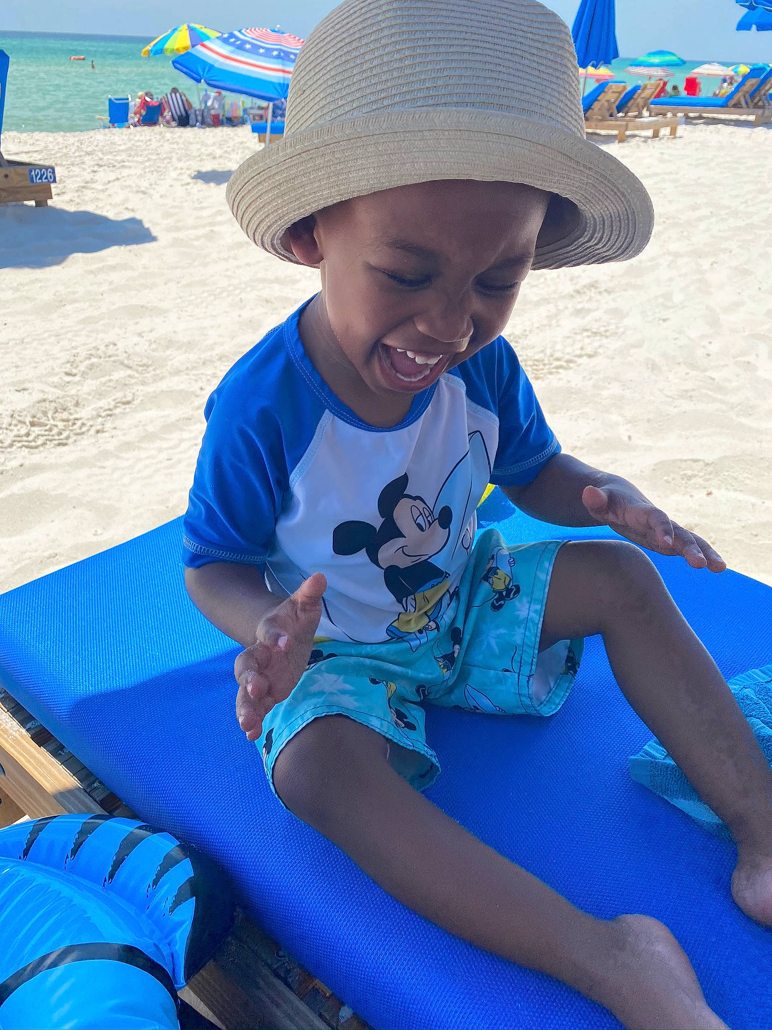 Carter joined the competition — help win amazing prizes! beach, blue, child, fashion_accessory, fun, hat, headgear, joy, leisure, outdoor_furniture, person, play, sand, sea, sitting, smile, summer, sun_hat, sun_tanning, toddler