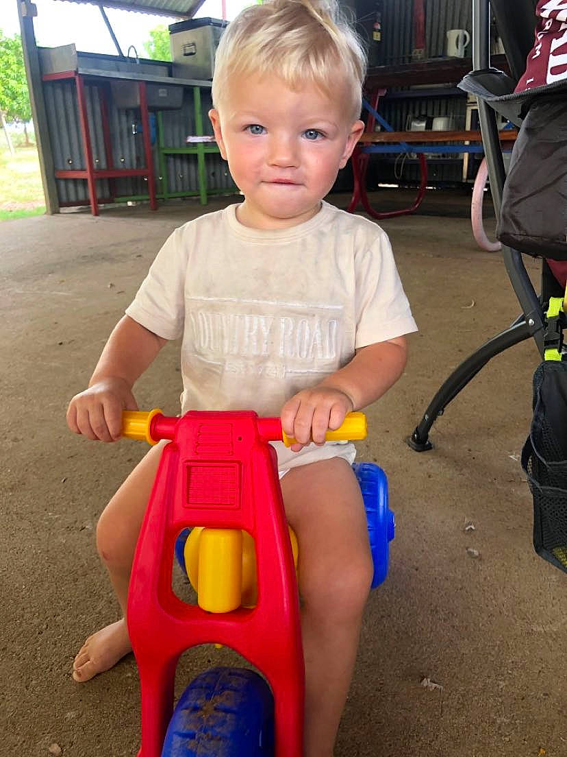 Huxley is registered to the contest to win money with this photo: baby, chair, child, city, electric_blue, fun, human_body, human_leg, knee, lap, leg, leisure, person, play, recreation, riding_toy, shorts, sitting, thigh, toddler