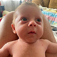 Asher is registered to the contest to win money with this photo: baby, infant, face, skin, person, legs, indoor, living_room, couch, blanket, curly_hair, wide_eyes, expression, close_up, child, human, torso, naked, background, soft_light