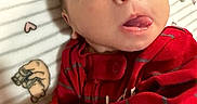 Antonio joined the competition — help win amazing prizes! baby, infant, tongue, red_clothing, striped_clothing, face, eyes, blanket, pattern, bear_pattern, heart_pattern, cute, child, newborn, portrait, lying_down, skin, expression, indoors, person