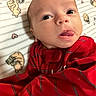 baby, infant, tongue, red_clothing, striped_clothing, face, eyes, blanket, pattern, bear_pattern, heart_pattern, cute, child, newborn, portrait, lying_down, skin, expression, indoors, person