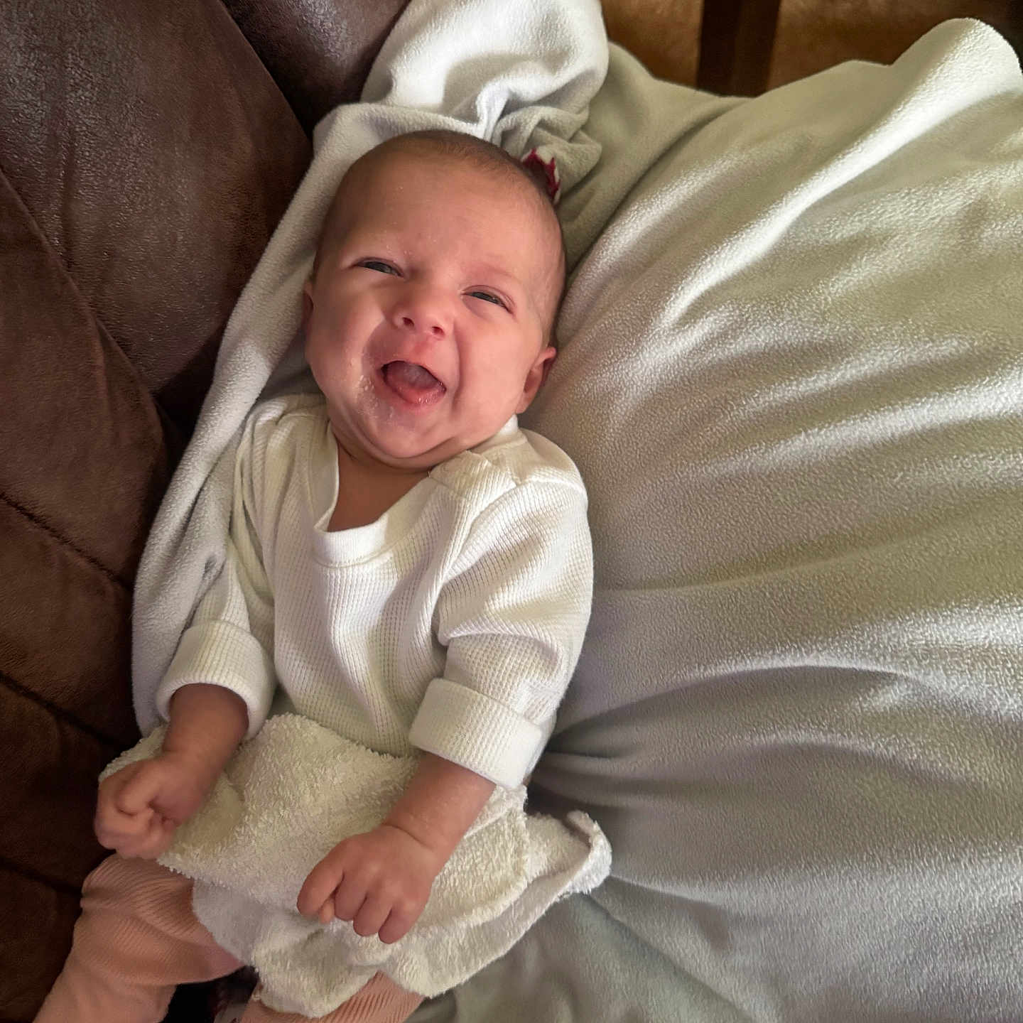 Nicole Lee is registered to the contest to win money with this photo: baby, blanket, couch, cozy, cute, face, hands, happy, indoor, infant, lying_down, newborn, pink_pants, portrait, smiling, socks, sofa, tongue_out, towel, white_shirt