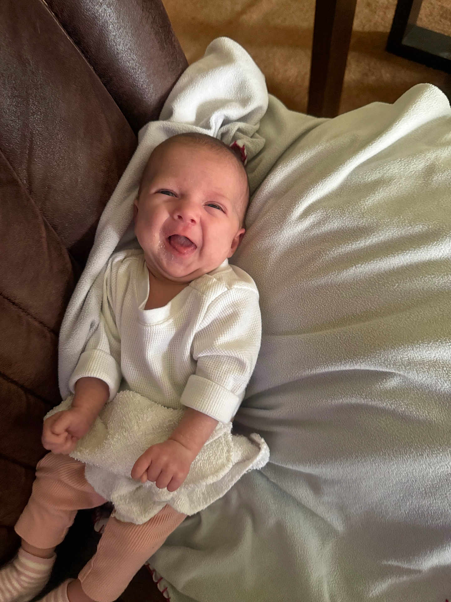 Nicole Lee is registered to the contest to win money with this photo: baby, infant, smiling, blanket, couch, white_shirt, pink_pants, socks, towel, happy, portrait, indoor, cute, lying_down, cozy, hands, face, tongue_out, newborn, sofa