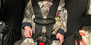 Dominick is registered to the contest to win money with this photo: baby, child, car_seat, pajamas, straps, seatbelt, infant, patterned_clothing, indoors, cute, blue_eyes, looking_up, sitting, young_child, car_safety, soft_lighting, head_support, comfort, expression, small_hands