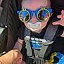 baby, sunglasses, pacifier, child, reflection, hand, black_shirt, car_seat, harness, toy, blue, yellow, outdoor, person, infant, cute, holding_hand, smile, casual, sunlight