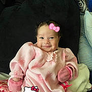 Amora is registered to the contest to win money with this photo: baby, infant, pink_clothing, mittens, smile, cute, cozy, blanket, cushion, indoors, lying_down, face, head, child, soft_texture, hello_kitty, graphic_overlay, happy, portrait, warm