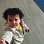 Léa a rejoint le concours — aidez-le/la à gagner de superbes lots ! toddler, child, curly_hair, jacket, yellow_shirt, indoor, wooden_floor, blue_rug, reaching_hand, person, young_child, casual_clothing, cute, portrait, looking_away, standing, flooring, home, curious, small_hand