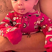 Nathaniel is registered to the contest to win money with this photo: baby, child, infant, portrait, face, smiling, tongue, wide_eyed, pink_clothing, pajamas, onesie, vehicle_pattern, adult, hands, holding, indoor, closeup, sitting, cozy, photography