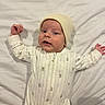 baby, infant, hat, onesie, striped_clothing, bear_prints, lying_down, bed_sheet, white_background, cute, child, portrait, sleepwear, cozy, small_hands, expression, face, headwear, soft_lighting, indoor