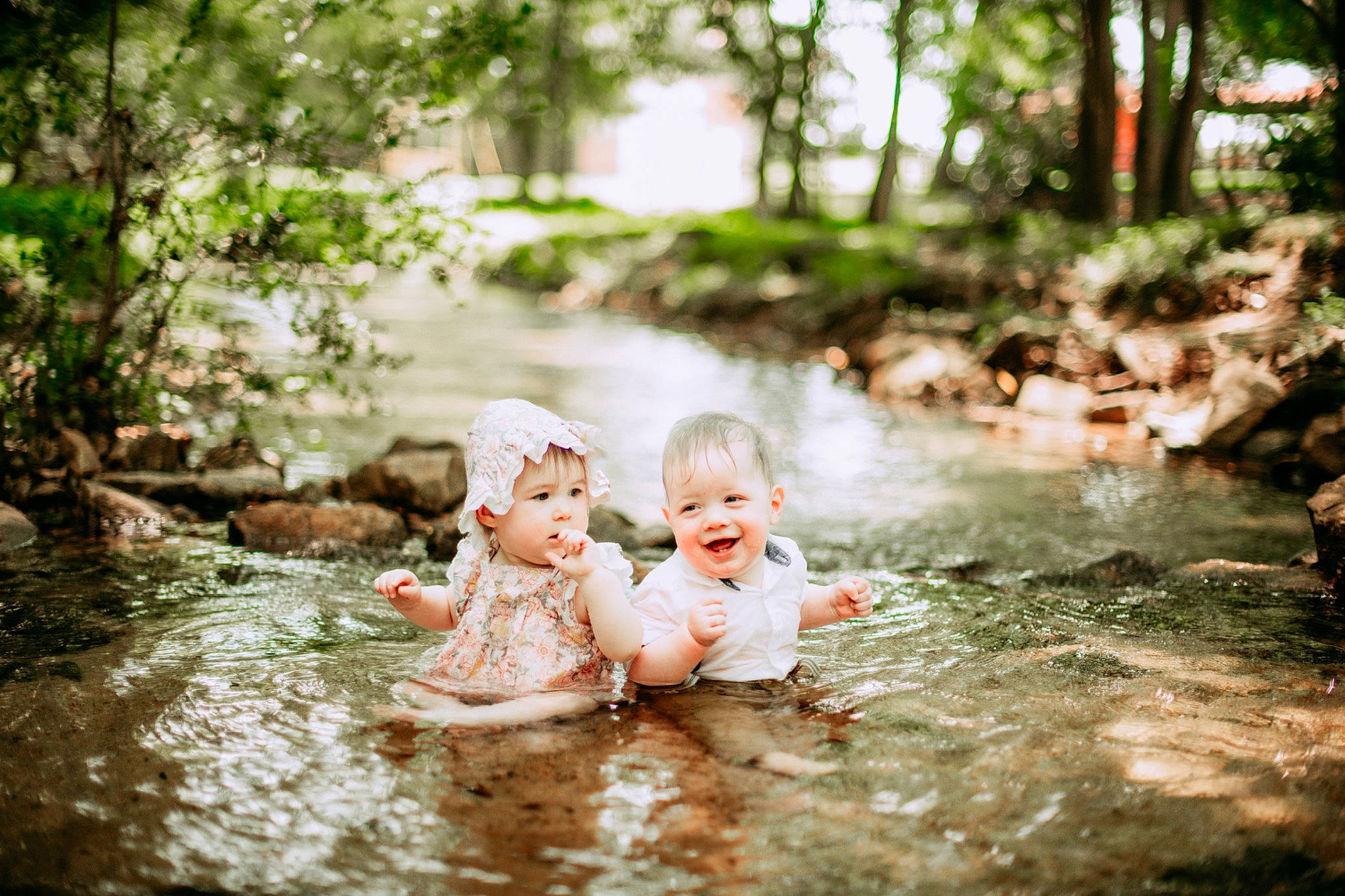 Alice is registered to the contest to win money with this photo: baby, bathing, forest, fun, grass, happy, headwear, joy, landscape, leisure, natural_landscape, people_in_nature, person, plant, recreation, smile, stream, summer, sunlight, toddler