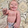 baby, smiling, diaper, infant, bare_chest, blanket, pattern, fabric, happy, cute, child, laying_down, clothing, fist, playful, comfort, indoors, person, portrait, toddler