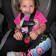 Eimy is registered to the contest to win money with this photo: toddler, child, car_seat, pacifier, pink_shirt, heart_design, leggings, sneakers, curly_hair, hair_clip, safety_harness, car_interior, seatbelt, cute, young_child, portrait, indoor, casual_clothing, footwear, baby