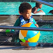 Jeremy joined the competition — help win amazing prizes! beach_ball, blue, child, colorful, curly_hair, fun, green, life_vest, outdoor, person, play, pool, railing, reflection, summer, sunlight, swimming, toddler, water, water_splash