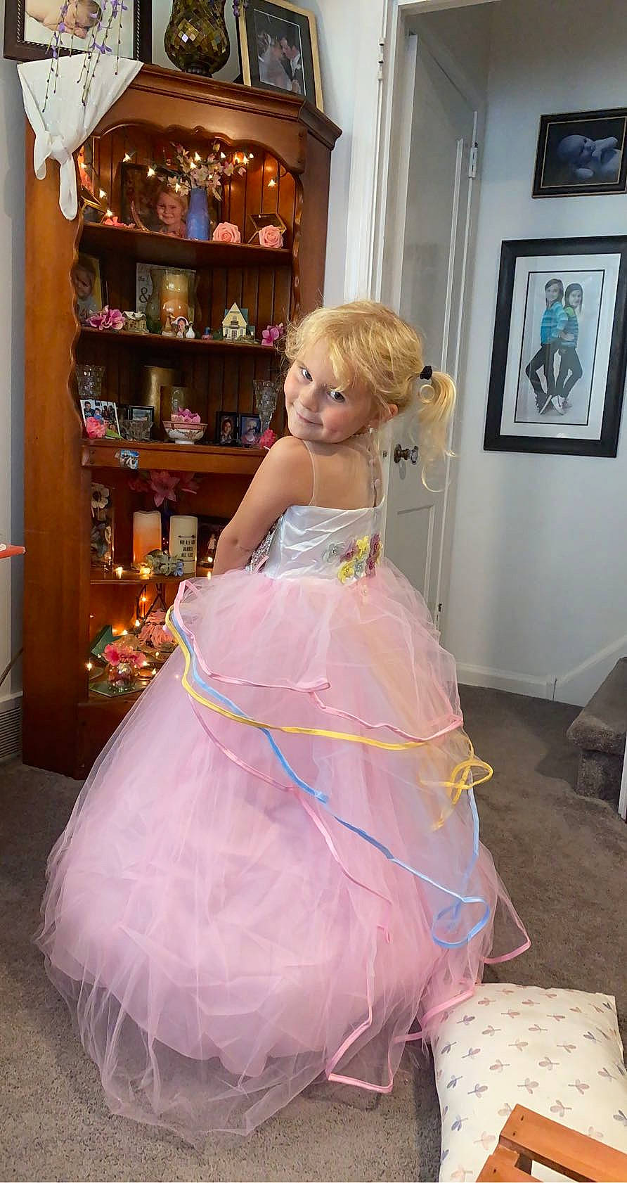 Payton is registered to the contest to win money with this photo: bridal_accessory, day_dress, dress, embellishment, event, fashion, fashion_design, formal_wear, gown, joy, long_hair, one_piece_garment, person, picture_frame, pink, purple, ruffle, shelf, smile, textile