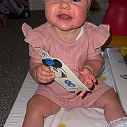 Aliyah joined the competition — help win amazing prizes! baby, child, pink_outfit, headband, mickey_mouse, card, sitting, smiling, play_mat, white_shoes, lace_socks, indoor, carpet, toy, happy, cute, face, person, infant, colorful