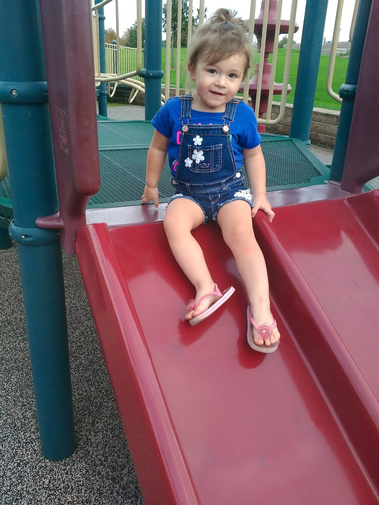 Arabella is registered to the contest to win money with this photo: arm, child, day, fun, girl, leg, leisure, outdoor_play_equipment, person, pink, play, playground, playground_slide, recreation, red, shoulder, sitting, standing, summer, toddler