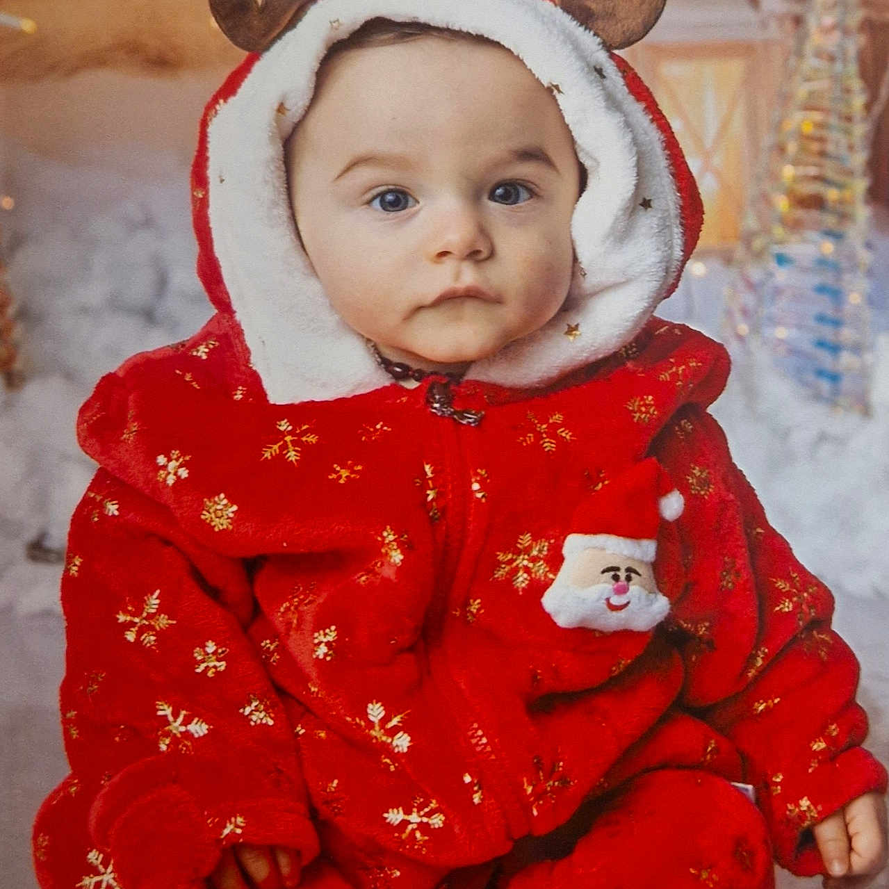 Isaac a rejoint le concours — aidez-le/la à gagner de superbes lots ! baby, calm_expression, child, christmas, cute, decorations, festive_lighting, festive_outfit, holiday_theme, hood, indoor, portrait, red_clothing, reindeer_ears, santa_patch, sitting, snowflake_pattern, soft_texture, winter_clothing, young_child