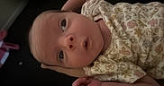Oaklynn joined the competition — help win amazing prizes! baby, baby_photo, blanket, child, close_up, cute, dark_background, face, family, floral_outfit, hands, head, indoor, infant, lying_down, onesie, patterned_clothing, portrait, soft_lighting, wide_eyes