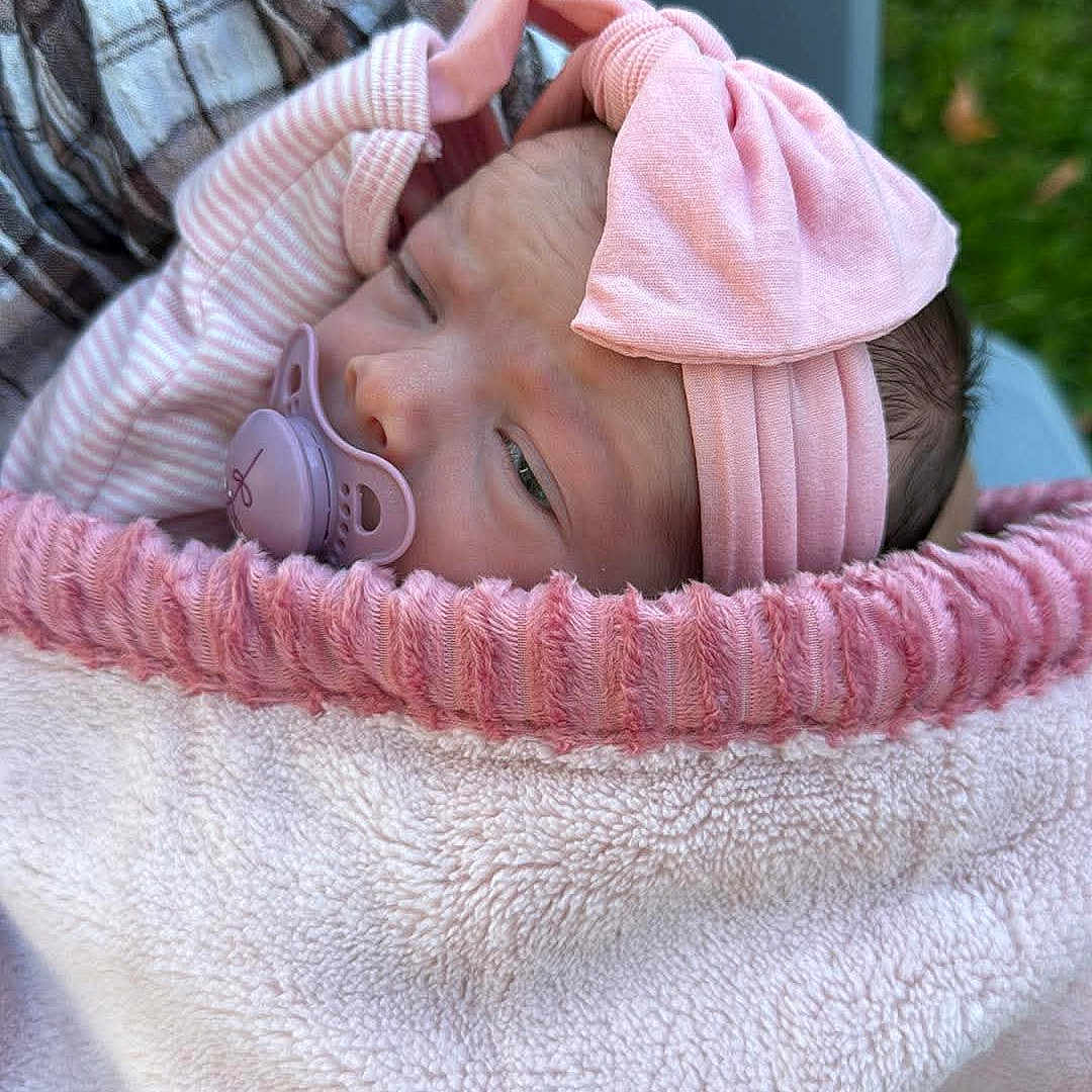 Oaklynn is registered to the contest to win money with this photo: newborn, baby, infant, child, portrait, sleeping, pacifier, pink, headband, bow, blanket, basket, cozy, outdoor, garden, seated, close_up, face, soft_texture, adorable