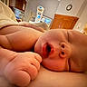newborn, baby, infant, hospital, patient_room, close_up, portrait, sleepy, face, head, hand, fingers, cuddling, blanket, bed, medical_equipment, iv_pump, clock, indoor, family