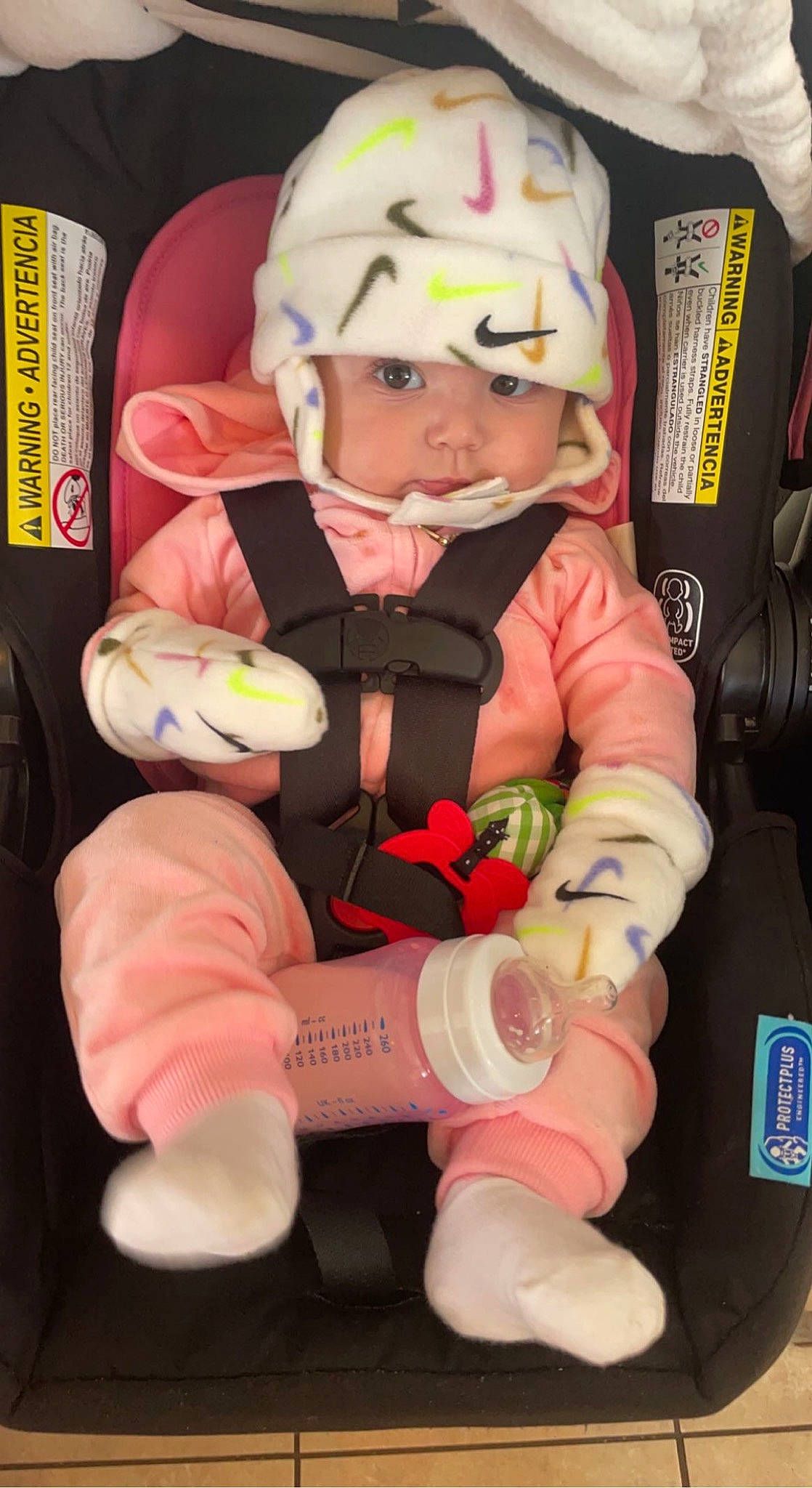 Cataléya is registered to the contest to win money with this photo: baby, baby_products, car_seat, carmine, child, comfort, fictional_character, finger, gesture, glove, headwear, human_leg, person, personal_protective_equipment, pink, service, sitting, sports_gear, thigh, thumb