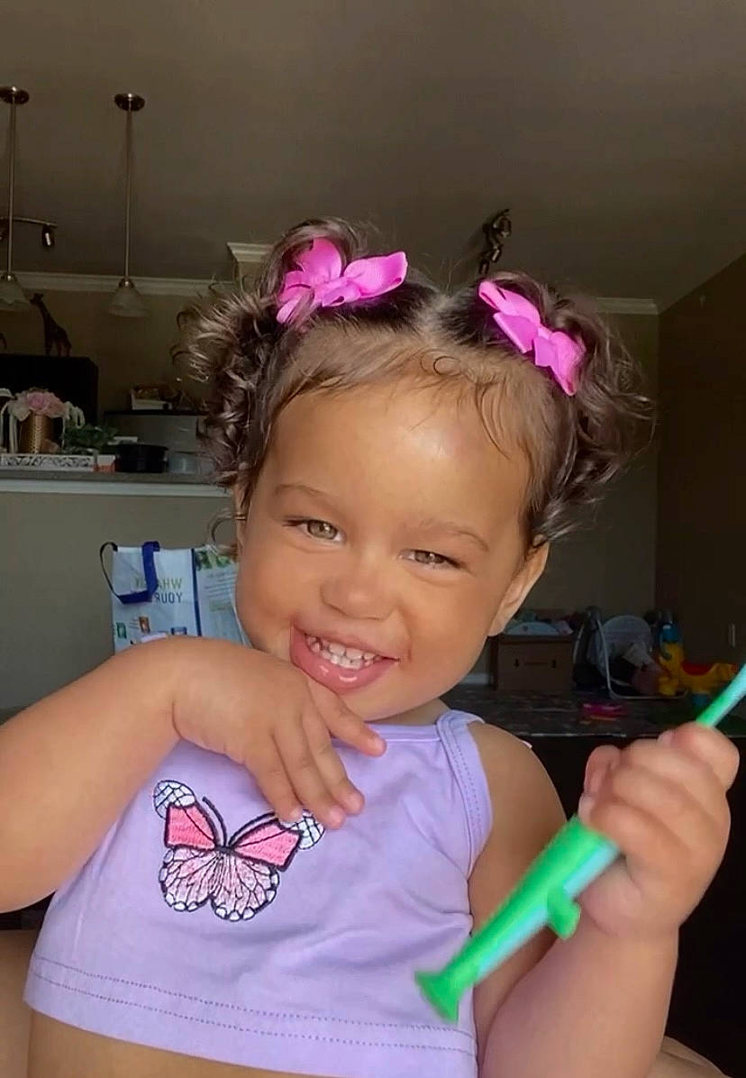 Stormi is registered to the contest to win money with this photo: arm, baby_toddler_clothing, cheek, child, ear, eyelash, facial_expression, finger, fun, hair, hand, happy, head, joy, magenta, person, pink, purple, smile, thumb