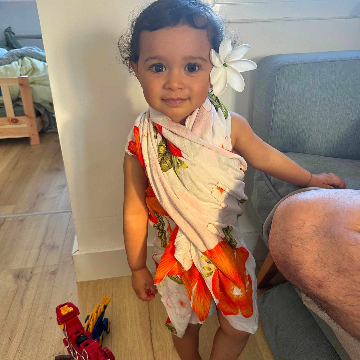 Heirava participe au concours pour gagner de l'argent avec cette photo : toddler, child, toy, dinosaur_toy, barefoot, flower, floral_cloth, indoor, wooden_floor, window, couch, person, smiling, curly_hair, playtime, home, furniture, skin, cute, portrait
