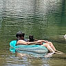 Lilith joined the competition — help win amazing prizes! man, cat, person, animal, river, water, inflatable_float, swimming, outdoor, nature, rocky_cliffs, lake, floating, relaxing, sunglasses, cap, black_cat, tabby_cat, reflection, summer
