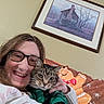 Princess joined the competition — help win amazing prizes! blanket, cat, couch, cozy, face, framed_art, fur, gingerbread_man, glasses, green_clothing, holiday_theme, home, indoor, painting, person, portrait, smile, sweater, tabby_cat, wall