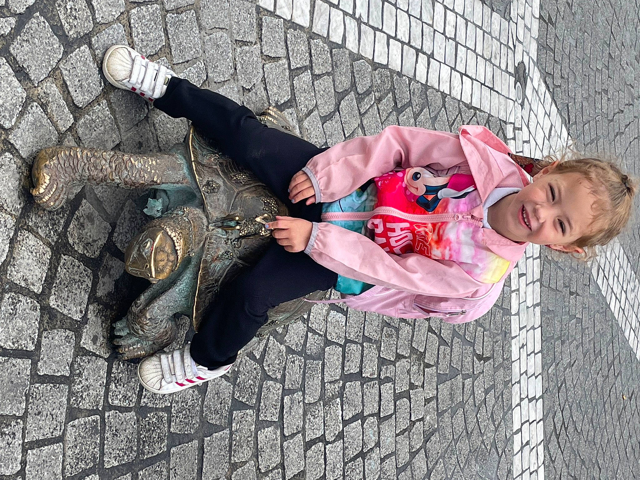 Athena a rejoint le concours — aidez-le/la à gagner de superbes lots ! child, city, cobblestone, fun, grass, happy, human_leg, joy, leisure, pattern, pedestrian, person, road_surface, shadow, sidewalk, sitting, street, toddler, tree