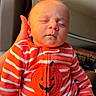 newborn, baby, sleeping, infant, child, face, portrait, car_seat, vehicle, orange, striped_clothing, pumpkin, halloween, onesie, seated, peaceful, closed_eyes, indoor, automotive, family