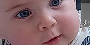 Matthew is registered to the contest to win money with this photo: baby, blanket, blue_eyes, child, chubby_cheeks, close_up, curious, cute, expression, face, hand, indoors, infant, leaf_pattern, lying_down, portrait, shirt, skin, soft_lighting, young
