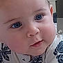 Matthew is registered to the contest to win money with this photo: baby, child, face, blue_eyes, chubby_cheeks, curious, close_up, infant, leaf_pattern, shirt, blanket, lying_down, soft_lighting, indoors, cute, portrait, skin, hand, young, expression