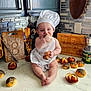 Athena joined the competition — help win amazing prizes! apron, baby, bread, bun, chef_hat, child, cooking, countertop, cute, cutting_board, flour, food, indoor, kitchen, person, poppy_seeds, sitting, smiling, tongs, utensils