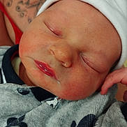 Malone participe au concours pour gagner de l'argent avec cette photo : baby, newborn, sleeping, drool, hat, clothing, whale_pattern, tattoo, arm, closeup, face, infant, cute, peaceful, soft_skin, child, person, portrait, resting, cozy