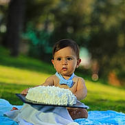 Milan a rejoint le concours — aidez-le/la à gagner de superbes lots ! baby, child, blue_bow_tie, cake, cream, frosting, outdoor, grass, blanket, cute, face, food, sitting, young_child, portrait, nature, summer, expression, celebration, fun