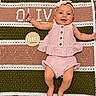 baby, child, infant, smiling, pink_clothing, headband, bow, crochet_blanket, wooden_plaque, three_months, happy, lying_down, face, cute, skin, floor, patterned_rug, decor, portrait, indoors
