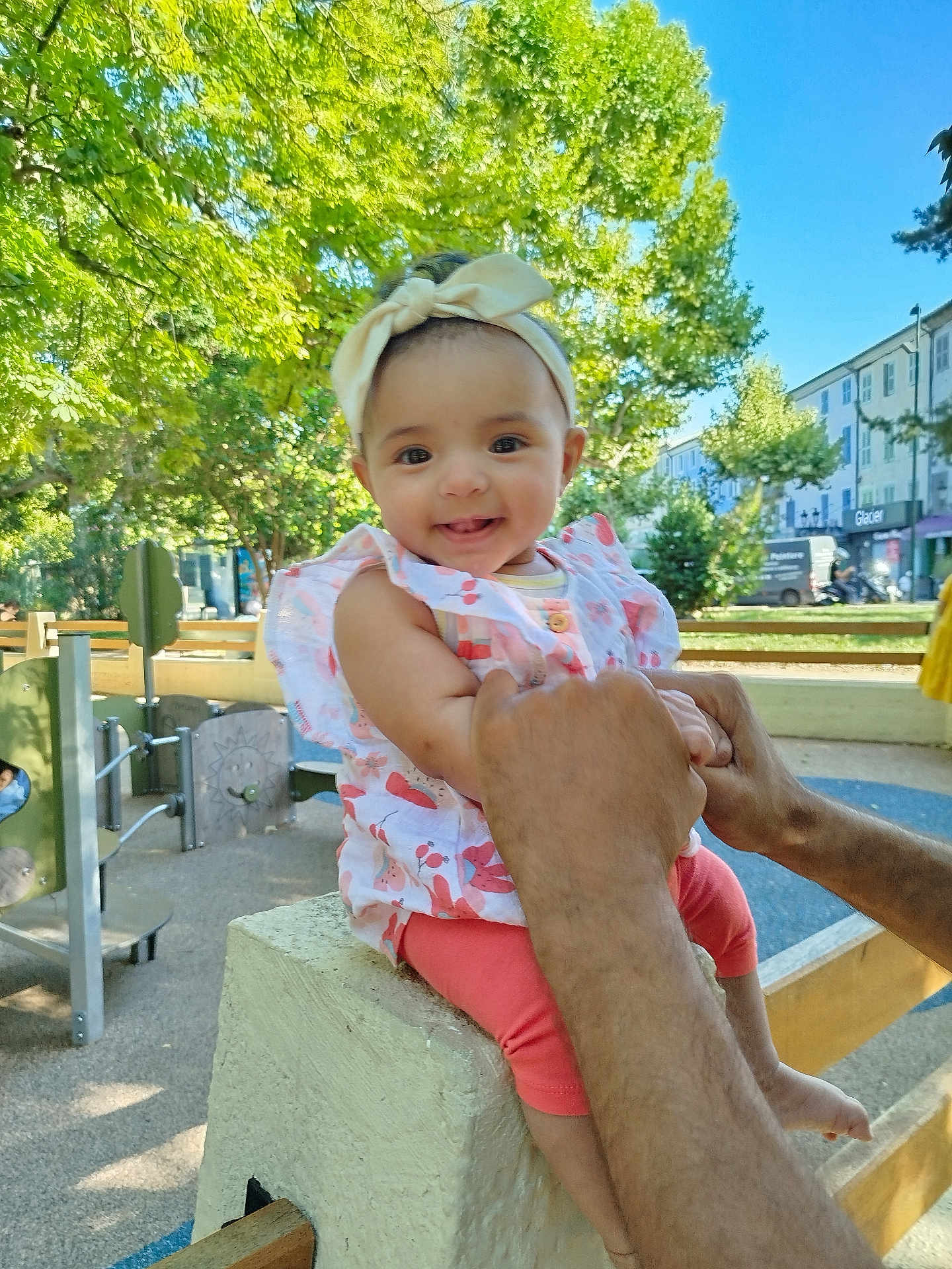 Oumayia joined the competition — help win amazing prizes! baby, child, smiling, headband, outdoor, playground, trees, sunny, concrete, hands, person, happy, clothing, park, daylight, building, bench, fence, infant, cute