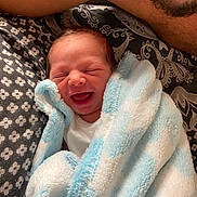 Rhys Junior is registered to the contest to win money with this photo: newborn, baby, smile, blanket, blue, white, pattern, fabric, person, adult, beard, closeup, happy, cozy, bed, wrapped, face, infant, portrait, love