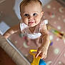 Alexandrya is registered to the contest to win money with this photo: baby, child, smiling, blue_eyes, pink_clothing, toy, yellow_toy, playpen, indoor, cute, reaching, hand, face, infant, young_child, happy, person, blurred_background, soft_lighting, floor_mat