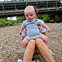 Eli joined the competition — help win amazing prizes! baby, child, person, legs, outdoor, rocky_ground, bridge, sneakers, phone, blue_clothing, sitting, nature, curious, shorts, socks, tattoo, adult, holding, summer, casual