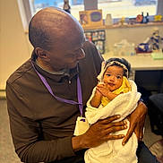 Zaphorah joined the competition — help win amazing prizes! man, baby, child, indoor, blanket, holding, headband, smiling, affection, love, person, portrait, seated, clothing, adult, hands, office, window, furniture, warm