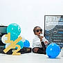 Teo joined the competition — help win amazing prizes! baby, child, sunglasses, bottle, balloons, briefcase, milestone_board, white_background, black_tie, celebration, half_birthday, blue_balloons, white_balloons, sitting, portrait, infant, floor, cute, smiling, party