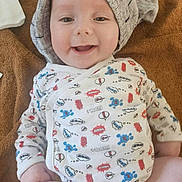 Roland participe au concours pour gagner de l'argent avec cette photo : baby, smiling, onesie, knitted_cap, blanket, happy, infant, cute, child, face, clothing, patterned, indoor, soft_texture, skin, laying_down, joy, expression, young_child, comfort