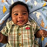 Jermany joined the competition — help win amazing prizes! baby, smiling, plaid_shirt, blanket, dinosaur_pattern, child, portrait, indoor, happy, cute, infant, person, clothing, buttoned_shirt, lying_down, closeup, face, cheerful, soft_texture, casual