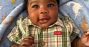 Jermany joined the competition — help win amazing prizes! baby, child, smiling, plaid_shirt, buttoned_shirt, blanket, dinosaur_pattern, blue_blanket, curly_hair, indoor, portrait, happy, infant, cute, skin, face, hand, lying_down, cozy, clothing