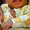baby, infant, smiling, happy, face, onesie, clothing, lion_pattern, hand, skin, person, cute, joy, child, sleepwear, newborn, adorable, portrait, soft, closeup