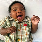 Jermany joined the competition — help win amazing prizes! baby, smiling, plaid_shirt, infant, happy, lying_down, pillow, baby_bottle, curly_hair, child, cute, indoors, toddler, young_child, green, orange, fabric, clothing, portrait, hands